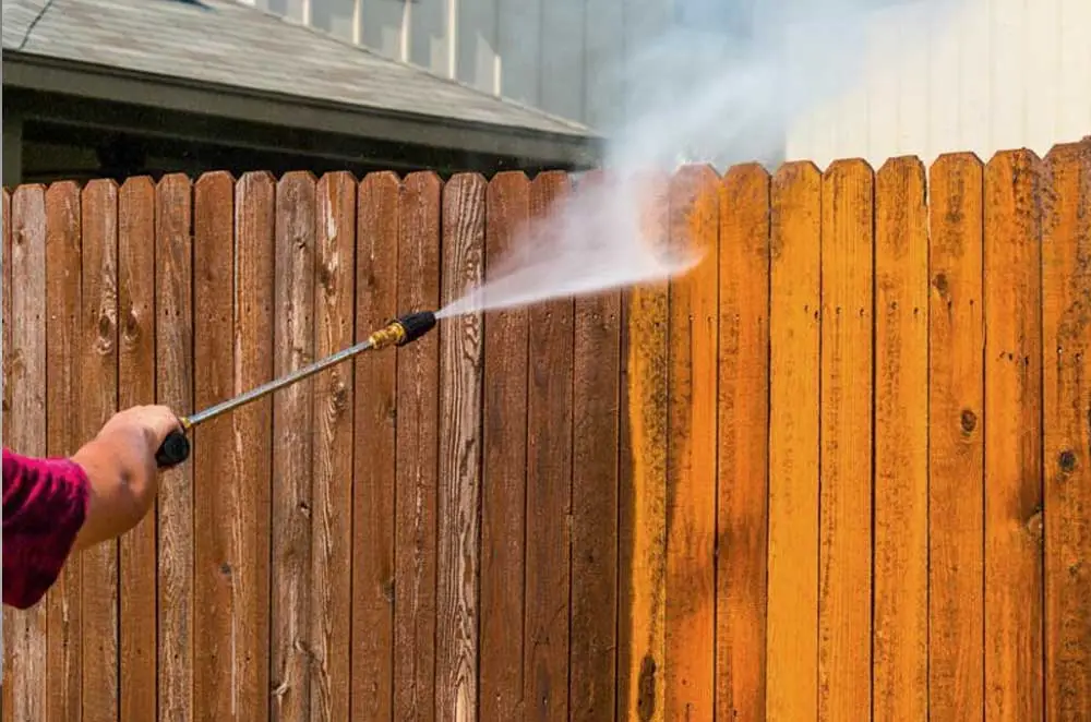 a fence being power washed